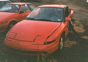 Banged-up red 1995 Saturn SC2